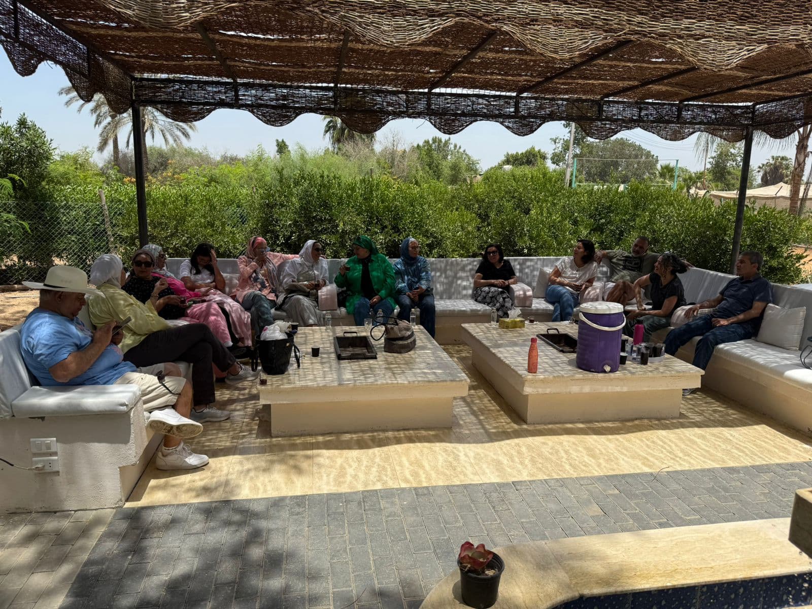 Guests gathered around long outdoor tables under a shaded canopy